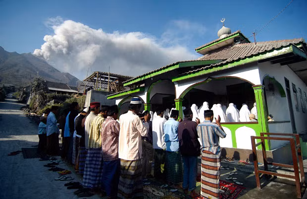 Villagers pray during Eid al-Adha in Selo Village, Boyolali, Indonesia, while Mount Merapi erupts 