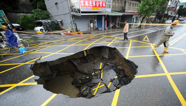 Kinh hoàng những hố địa ngục trên thế giới ảnh 3 October 2010: People walk past a sinkhole caused by typhoon Megi in Suao, in Taiwan’s eastern Ilan county