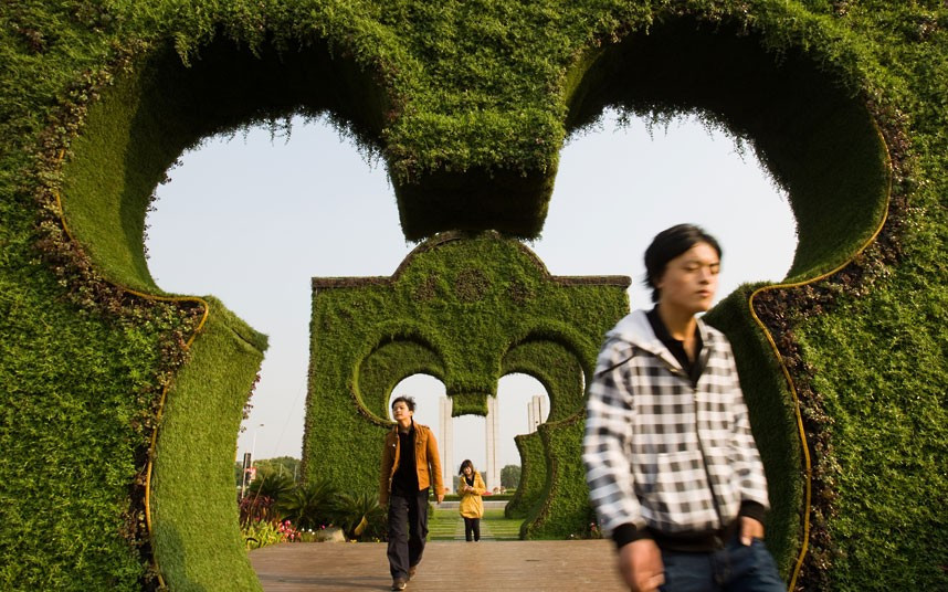 People walk through Mickey Mouse-shaped hedges at Shayan Square in Shanghai, China