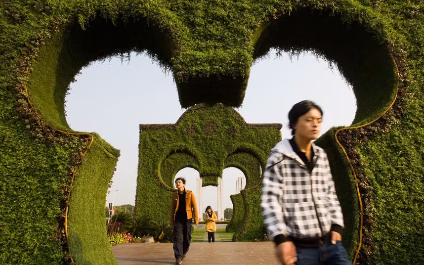 People walk through Mickey Mouse-shaped hedges at Shayan Square in Shanghai, China