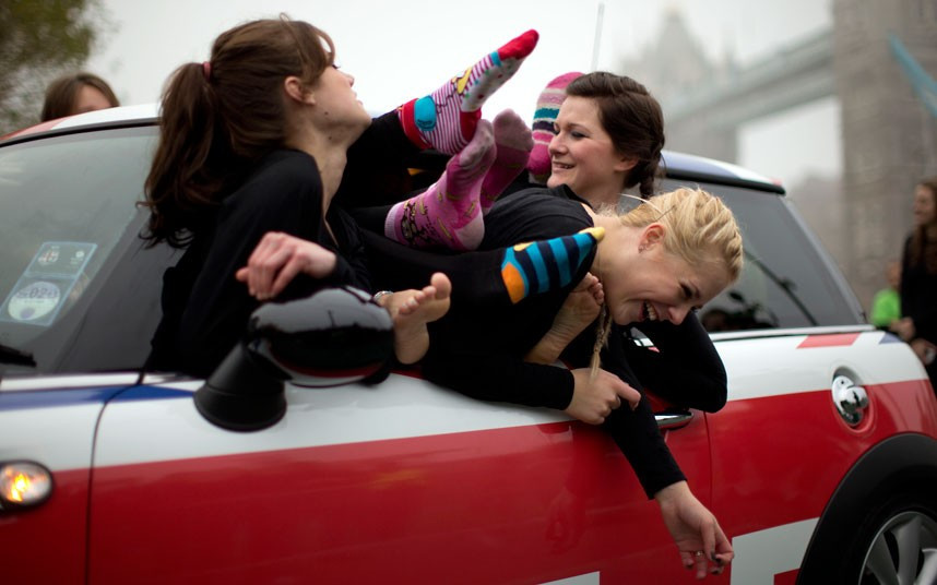 Participants laugh as they get into position to pose for photos after a successful Guinness World Record attempt to fit 28 people into a Mini. The attempt, which broke the previous record of 27 people, was set at Potters Field near Tower Bridge on Guinness World Records Day.