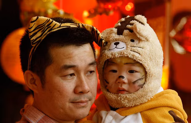 A man and his baby, both dressed up in tiger costumes, take part in a baby crawling contest at a shopping mall in Hong Kong