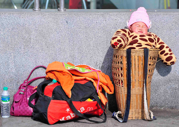Khoảng 150 triệu người Trung Quốc chen chân về quê ăn Tết ảnh 4 A baby sits in a basket while waiting to board a train at a railway station in Nanjing, Jiangsu province