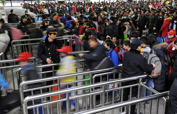 Khoảng 150 triệu người Trung Quốc chen chân về quê ăn Tết ảnh 11 Passengers move through barriers to board a train at a railway station in Beijing, taking the journey home for the Lunar New Year