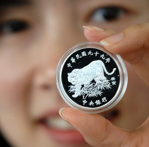A staff member of Taiwan’s central bank displays a coin issued to mark the year of the tiger