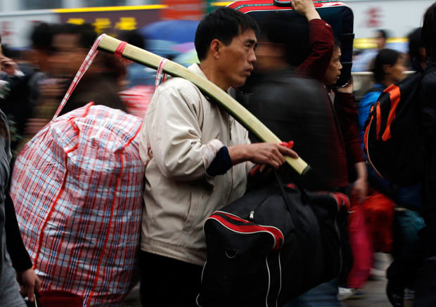 Khoảng 150 triệu người Trung Quốc chen chân về quê ăn Tết ảnh 6 A migrant worker carries his luggage as he makes his way towards a railway station in Guangzhou, in south China’s Guangdong province