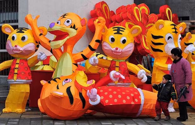 People walk past tiger lanterns on a street in Nanjing, Jiangsu province, China