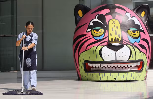 A worker cleans next to a tiger decoration set up at a shopping centre in Bangkok, Thailand