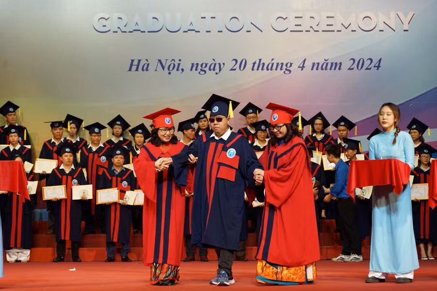 Lãnh đạo Trường ĐH Mở Hà Nội hỗ trợ sinh viên khiếm thị nhận bằng tốt nghiệp.