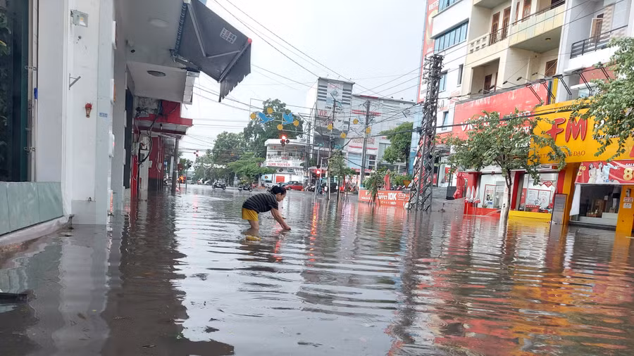 Người dân lội nước, vớt rác ở cống để nước nhanh chóng thoát, tránh ngập lụt.