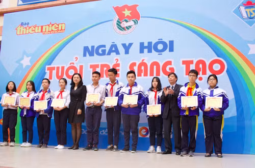 Ông Nguyễn Đức Quang - Tổng Biên tập báo Thiếu niên Tiền phong - (thứ ba từ phải qua) và bà Trần Lưu Hoa - Trưởng phòng GD&ĐT quận Hai Bà Trưng trao tặng các suất học bổng cho 10 em học sinh xuất sắc, vượt khó học tốt của THCS Tây Sơn.