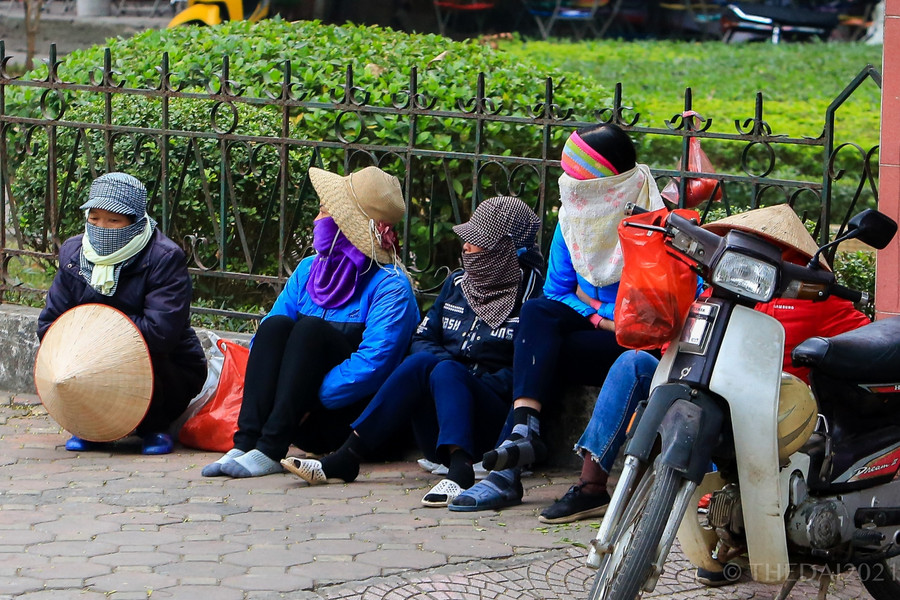 Nhiều người lao động tự do ngồi túm tụm tại một góc đường để cùng chống lạnh.