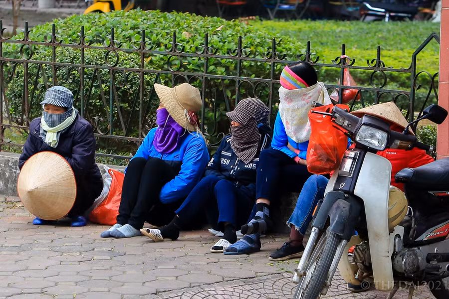 Nhiều người lao động tự do ngồi túm tụm tại một góc đường để cùng chống lạnh.