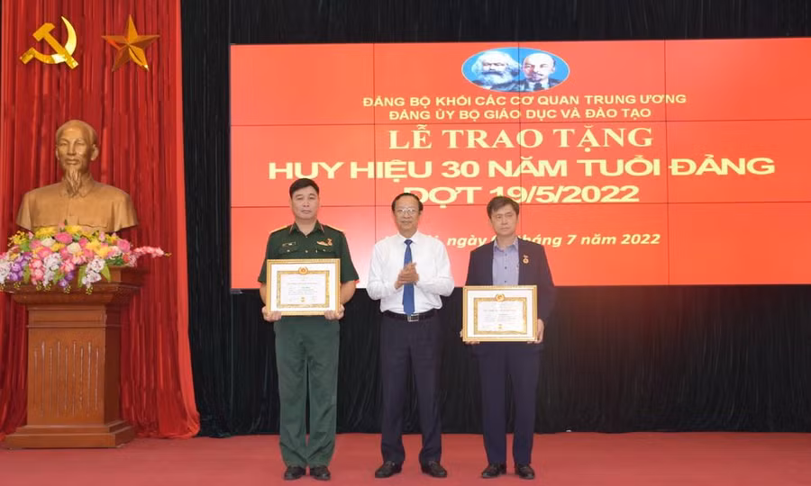 Đồng chí Trần Sâm (ngoài cùng bên phải) và đồng chí Vũ Minh được Thứ trưởng Phạm Ngọc Thưởng (ở giữa) trao Huy hiệu 30 năm tuổi Đảng