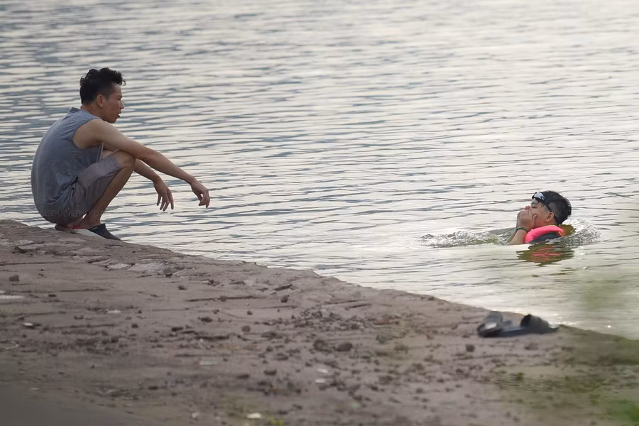 Những người tắm và bơi lội tại hồ Linh Đàm có nhiều lứa tuổi, nhiều trẻ em được phụ huynh trang bị phao và các thiết bị an toàn.