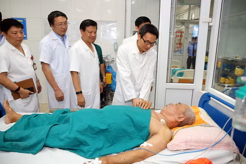 Phó Thủ tướng Vũ Đức Đam hỏi thăm một bệnh nhân cao tuổi mắc SXH đang điều trị tại Bệnh viện Nhiệt đới Trung ương. Ảnh: VGP