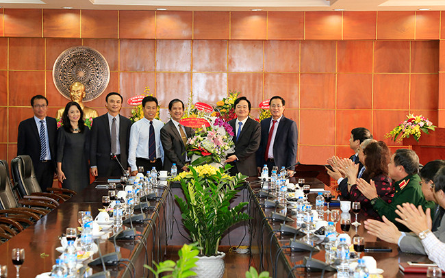 Bộ trưởng Phùng Xuân Nhạ (thứ 2 từ phải qua) nhận lẵng hoa chúc mừng từ đoàn cán bộ của Đại học Quốc gia Hà Nội