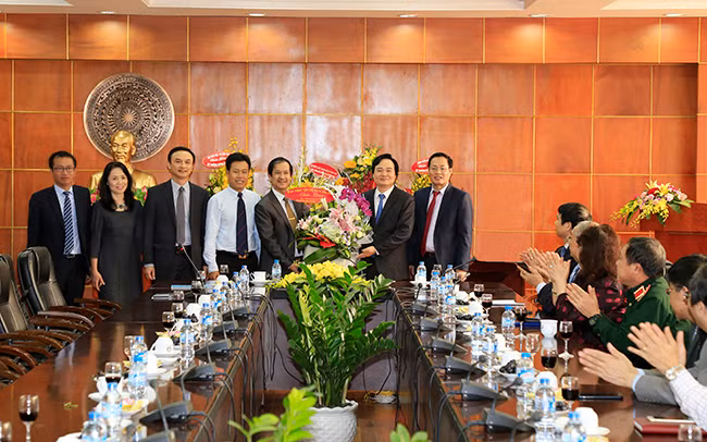 Bộ trưởng Phùng Xuân Nhạ (thứ 2 từ phải qua) nhận lẵng hoa chúc mừng từ đoàn cán bộ của Đại học Quốc gia Hà Nội