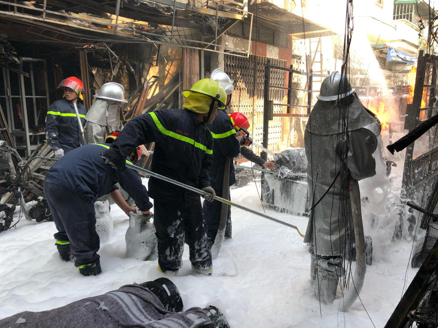 Lực lượng PCCC phun bọt và kéo từng bình gas đang cháy trên xe tải xuống.