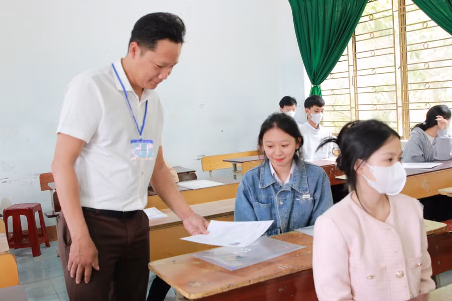 Cán bộ coi thi tại điểm thi Trường THPT Trần Hưng Đạo kiểm tra giấy tờ của thí sinh. (Ảnh: Thành Tâm)