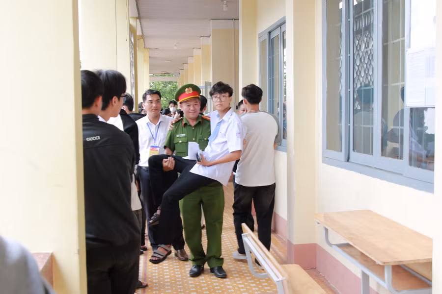 Lượng lượng công an tham gia bảo vệ điểm thi hỗ trợ thí sinh Nguyễn Đình Cương đến phòng thi. (Ảnh: Thành Tâm)