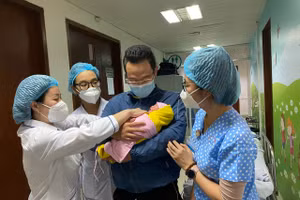 Bé gái chào đời khỏe mạnh và trong vòng tay của bố cùng các nhân viên y tế. Ảnh: BV.