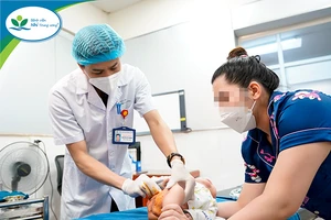 Bệnh nhi đang được bác sĩ Hoàng chăm sóc vết thương sau phẫu thuật. Nguồn: BV Nhi Trung ương.