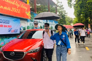 Lực lượng tình nguyện che ô hỗ trợ thí sinh tại điểm thi.