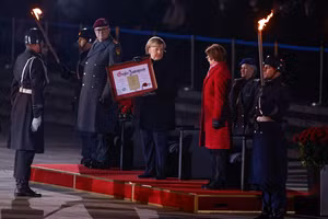 Bà Merkel nhận chứng nhận trong đại quân lễ.