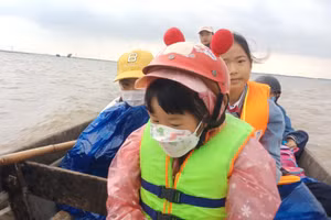 Học sinh mặc áo phao, đến trường bằng đò.