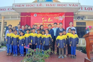 Thầy giáo Nguyễn Văn Tý trao quà cho học sinh khó khăn.