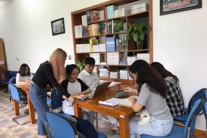 Nhóm 5 bạn sinh viên đang thảo luận một mô hình kinh doanh ảo tại thư viện trường.