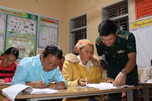 Thầy giáo Vì Văn Liêm, Đồn biên phòng Mường Lạn đang chỉ dẫn người dân đọc và viết chữ.