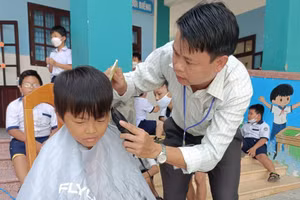 Thầy Bình cắt tóc cho học sinh ngay tại sân trường.