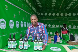 Một thành viên của Hợp tác xã Twitule bán chai rượu chuối tại hội chợ thương mại ở Blantyre, Malawi. Ảnh: COMSIP