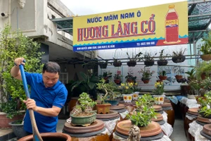 Anh Bùi Thanh Phú - giáo viên dạy Tin học Trường THPT Phạm Phú Thứ (TP Đà Nẵng), chủ xưởng sản xuất nước mắm Nam Ô Hương Làng Cổ, bên những chum nước mắm của gia đình.