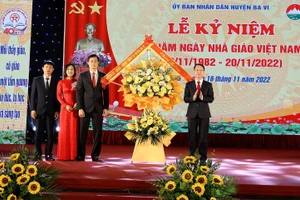 Ông Phùng Tân Nhị (phải) - Phó Bí thư thường trực Huyện ủy, Chủ tịch HĐND huyện Ba Vì thay mặt lãnh đạo huyện tặng hoa chúc mừng Phòng GD&ĐT Ba Vì.