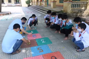 Thầy Phạm Ngọc An cùng học sinh vẽ ô bàn cờ để chơi nhảy lò cò. Ảnh: NVCC
