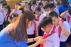 Cô giáo Trường Tiểu học Núi Thành hướng dẫn học sinh cách thắt khăn quàng đỏ trong Lễ kết nạp đội viên mới khối lớp Ba. 