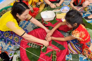 Cô giáo hướng dẫn học sinh tự tay gói bánh chưng trong hoạt động trải nghiệm Ngày Tết quê em.