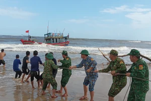 Các cán bộ, chiến sĩ biên phòng phối hợp người dân cứu hộ tàu mắc cạn.