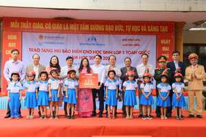 TS Lê Thị Hương, Giám đốc Sở GD&ĐT tỉnh Quảng Trị (thứ 3 bên trái), đại diện Ban An toàn giao thông tỉnh Quảng Trị... tặng mũ bảo hiểm cho học sinh.