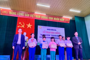 Ông Trần Bình Thuận - Chủ tịch UBND huyện Hướng Hóa (bên phải) và ông Nguyễn Thanh Hùng - Giám đốc Công ty TĐQT (bên trái) trao học bổng đến các em học sinh, sinh viên. Ảnh: Lê Phương.