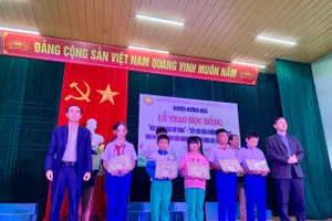 Ông Trần Bình Thuận - Chủ tịch UBND huyện Hướng Hóa (bên phải) và ông Nguyễn Thanh Hùng - Giám đốc Công ty TĐQT (bên trái) trao học bổng đến các em học sinh, sinh viên. Ảnh: Lê Phương.