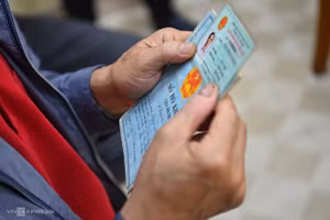 Một người dân cầm chứng minh thư và hộ khẩu giấy đi làm thẻ căn cước công dân gắn chip, ngày 9/3. Ảnh:Giang Huy