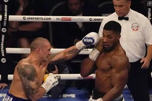 Usyk (trái) tung cú đấm tay trái vào Joshua hôm 26/9.