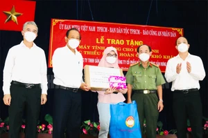 Nguyên Phó Thủ tướng thường trực Chính phủ Trương Hòa Bình cùng đại diện lãnh đạo TP Hồ Chí Minh trao tặng máy tính xách tay cho em Asikine Hồng, học sinh lớp 12 Trường THPT Tạ Quang Bửu (Ảnh: Thành ủy TP).