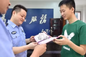 Wu Jinlin (phải) khoe thư mời nhập học với các sĩ quan cảnh sát.