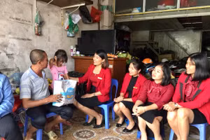 Cô Nguyễn Thị Cẩm Linh (thứ 3 từ trái sang) trao quà cho gia đình có hoàn cảnh khó khăn.