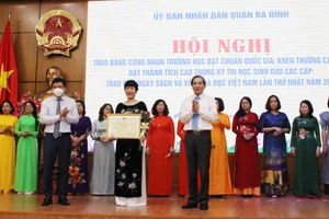 Bí thư Quận ủy Hoàng Minh Dũng Tiến (bên phải) và Chủ tịch UBND quận trao bằng khen cho giáo viên. 